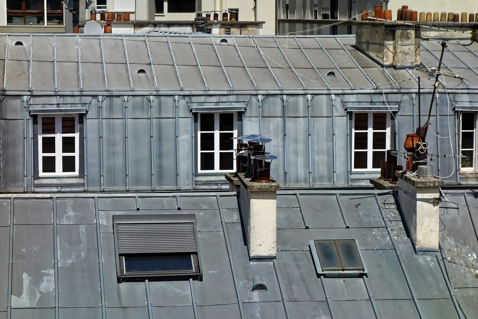 Toits en zinc d’un immeuble parisien, cheminées et fenêtres de chambres de bonne